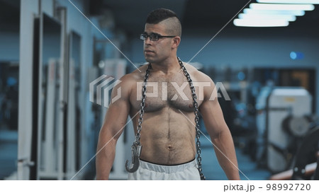 Muscular Arab in the gym walks with a metal chain after a workout. 98992720