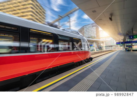 Red high speed train in motion on the railway station at sunset 98992847