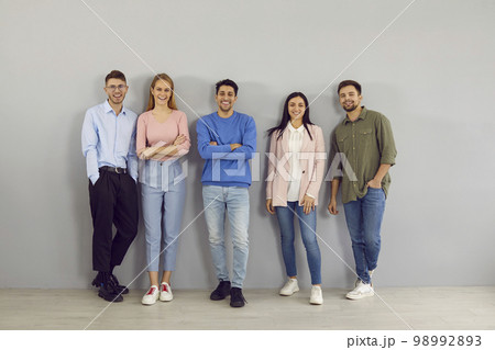 Portrait of group of different positive smart young people on gray wall background. Portrait of group of different positive smart young people on gray wall background. 98992893