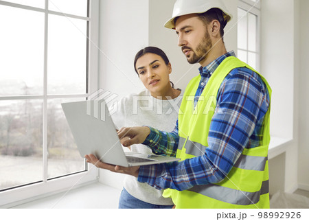 Builder or architect together with young woman discussing house construction and using laptop 98992926