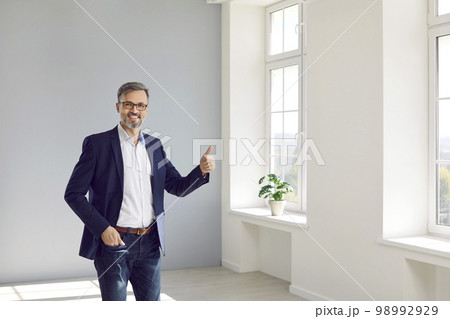 Joyful male realtor or real estate agent showing thumb up while standing in new building. Joyful male realtor or real estate agent showing thumb up while standing in new building. 98992929
