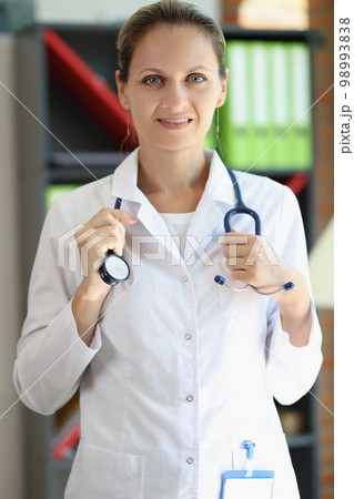 Smart female doctor holding stethoscope and looking at camera. 98993838