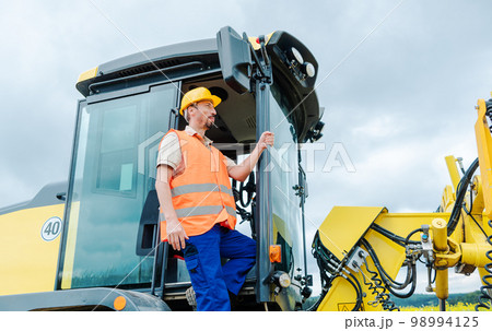 Construction worker on excavator planning the work to be done Construction worker on excavator planning the work to be done 98994125