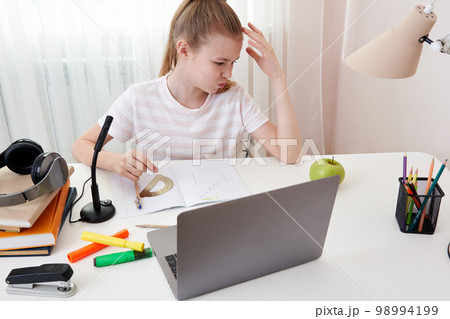 Teenage girl studying via video conference, e-learning with teacher and classmates on computer at home. Homeschooling and distance learning ,online education concept Teenage girl studying via video conference, e-learning with teacher and classmates on computer at home. Homeschooling and distance learning ,online education concept 98994199