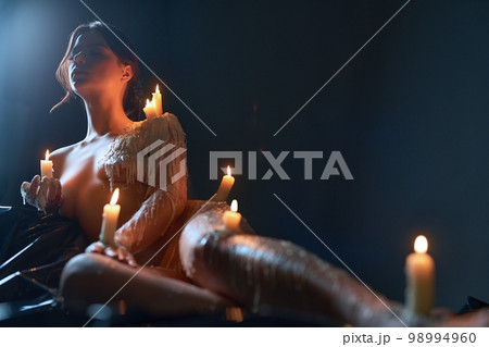 Naked woman with burning candles on body 98994960