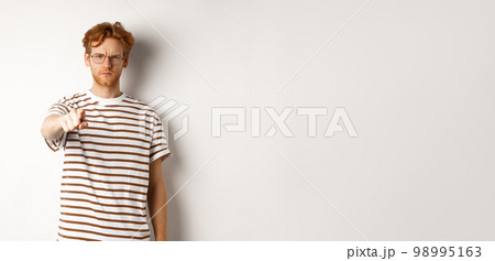 Angry and serious guy with red hair accusing you, frowning and pointing finger at camera, blame someone, standing over white background Angry and serious guy with red hair accusing you, frowning and pointing finger at camera, blame someone, standing over white background 98995163