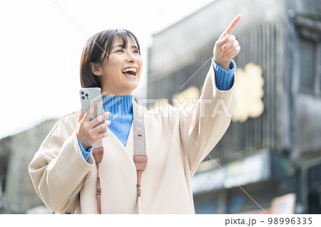 スマートフォンを持つ女性、旅行、観光、一人旅、笑顔、カメラ、撮影、記念写真、成人女性、タブレット 98996335