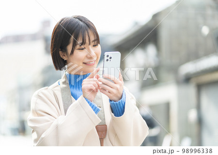スマートフォンを持つ女性、旅行、観光、一人旅、笑顔、カメラ、撮影、記念写真、成人女性、タブレット 98996338