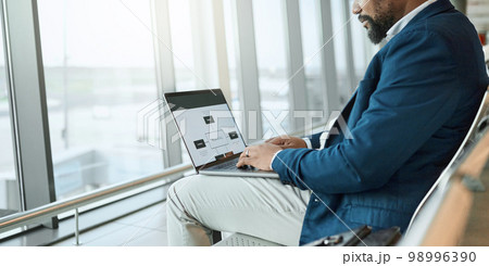 Travel, businessman and at an airport working on a laptop and waiting at terminal or boarding lounge. Entrepreneur, corporate or employee using computer at airline hub about to go on a flight 98996390