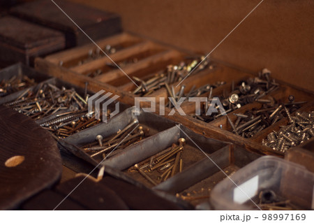 Old wooden toolbox with iron nails, screws, bolts and nuts. Storage of construction supplies in workshop. Male work box. Old wooden toolbox with iron nails, screws, bolts and nuts. Storage of construction supplies in workshop. Male work box. 98997169