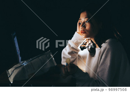 夜中に不摂生な生活をする若い女性の写真 98997508