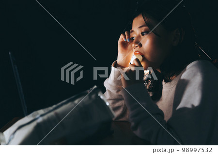 夜中に不摂生な生活をする若い女性の写真 98997532