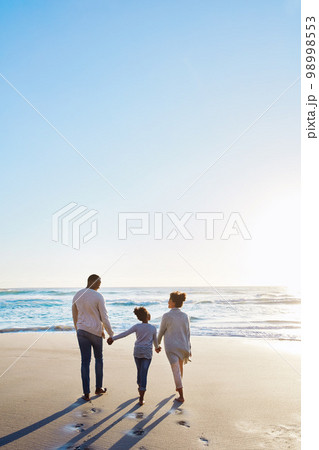 Family, beach and walk during sunset on vacation or holiday relaxing and enjoying peaceful scenery at the ocean. Sea, water and parents with daughter, child or kid with childhood freedom 98998553