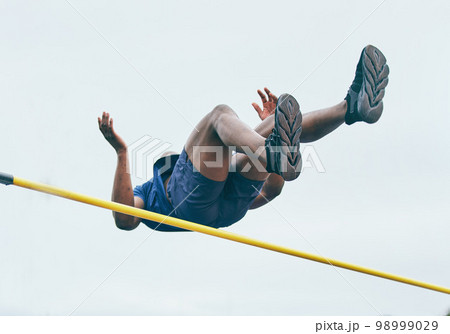 Fitness, athletics high jump by man at a stadium for training, energy and cardio against sky background. Jumping, athlete and male outdoors for performance, endurance and competition on mock up 98999029