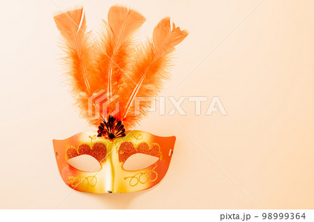 Happy Purim carnival decoration. Top view venetian ball mask with red feather on pastel background with copy space, Masquerade party, Jewish Purim in Hebrew, holiday background banner design 98999364