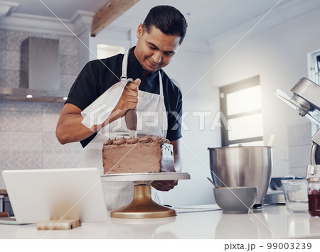 Piping, decorating and man baking a cake with chocolate in a kitchen or pastry chef happy with online recipe. Food, desert and cook preparing a sweet meal in Brazil and using a tablet Piping, decorating and man baking a cake with chocolate in a kitchen or pastry chef happy with online recipe. Food, desert and cook preparing a sweet meal in Brazil and using a tablet 99003239