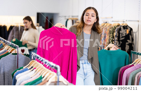 Woman customer choosing long sleeve shirt in store Woman customer choosing long sleeve shirt in store 99004211