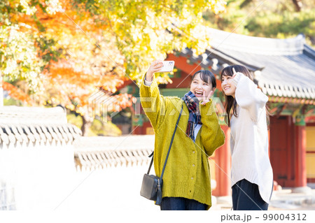 スマホで記念写真を撮る若い女性 99004312