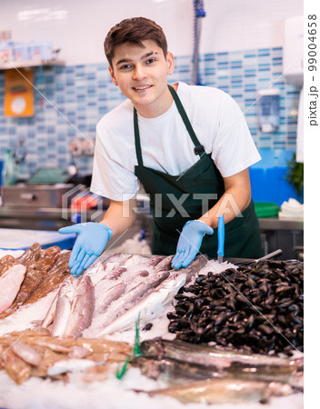 Positive salesman demonstrating lucet fish in fish store Positive salesman demonstrating lucet fish in fish store 99004658