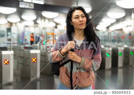 Asian woman passing through ticket gates in public transportation station 99004933