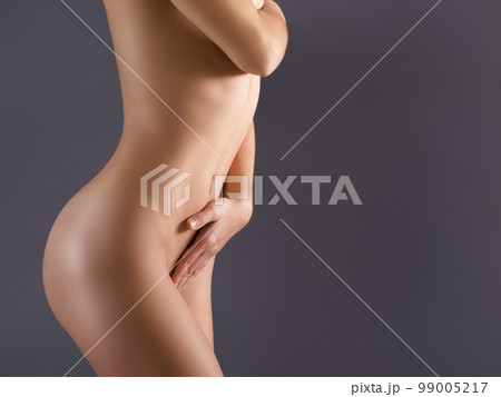 Naked, skin and nude woman in studio posing against a background with her smooth body. Young and sensual person covering breast with hand or sexy, beautiful and natural model with a tan Naked, skin and nude woman in studio posing against a background with her smooth body. Young and sensual person covering breast with hand or sexy, beautiful and natural model with a tan 99005217