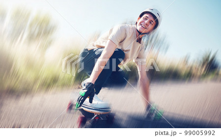 Skateboard, blurred motion and fast with a sports man skating on an asphalt road outdoor for recreation. Skate, soft focus and speed with a male athlete or skater training outside on the street 99005992