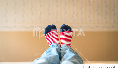 Woman's feet with colorful socks resting on bed. 99007228