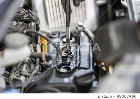 車のスパークプラグを交換する整備士 99007496