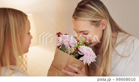Flowers, gift and happy with mother and girl for mothers day, birthday or congratulations in family home. Gratitude, smile and love with child giving bouquet to mom for present and celebration 99008010