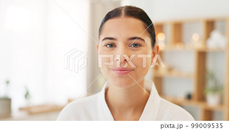 Face, portrait and woman at spa for skincare, luxury massage and wellness on a bed at a hotel. Happy, smile and beauty of a young girl at a salon to relax for peace and calm during cosmetic therapy 99009535