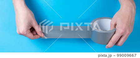 Woman holding silver scotch tape on blue background.  99009667
