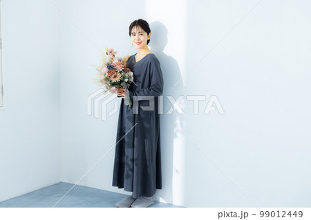 花束を持つグレーのワンピースの女性　 99012449
