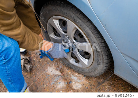 Hyundai wheel change, car is jacked up. Male hands unscrews wheel washers by ball wrench. Astana, Kazakhstan - 10.24.2022 Hyundai wheel change, car is jacked up. Male hands unscrews wheel washers by ball wrench. Astana, Kazakhstan - 10.24.2022 99012457