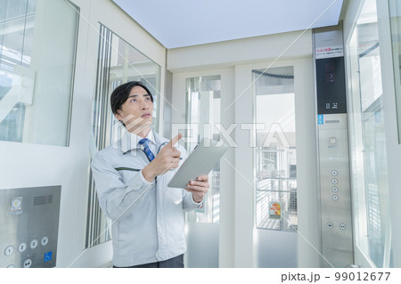 エレベーターを点検する作業服の男性 99012677