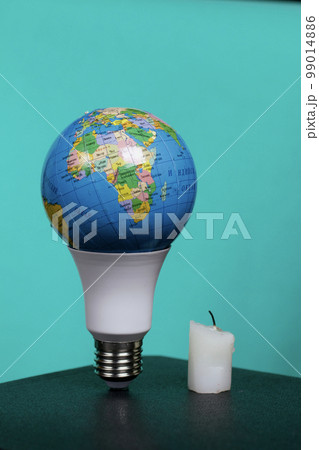 Light bulb with Earth planet model with space for text. Nearby is a candle stub. Global ecology, International Day of Energy Saving or Earth Hour concept. On a turquoise background. Light bulb with Earth planet model with space for text. Nearby is a candle stub. Global ecology, International Day of Energy Saving or Earth Hour concept. On a turquoise background. 99014886