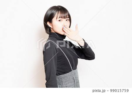 口を手で隠している若い女性 99015759