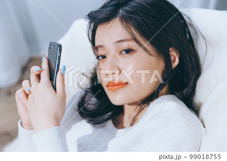 ソファーに寝転がる若い女性の写真 ソファーに寝転がる若い女性の写真 99018755