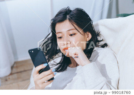 ソファーに寝転がる若い女性の写真 ソファーに寝転がる若い女性の写真 99018760