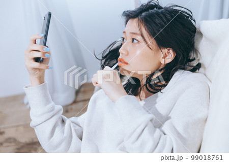 ソファーに寝転がる若い女性の写真 99018761