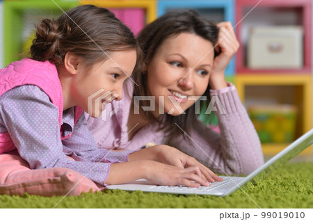 Mother with her little daughter using laptop 99019010