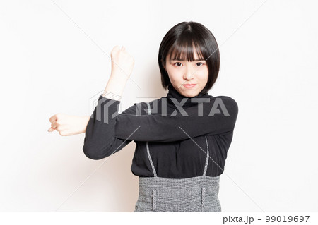 ストレッチをして腕を伸ばしている若い女性 99019697