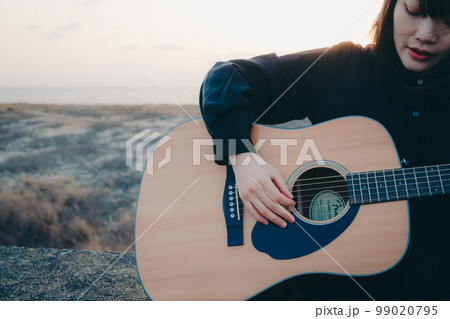 ギターを弾いている若い女性の写真 99020795