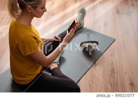 Young pretty woman using smartphone for yoga or workout online Young pretty woman using smartphone for yoga or workout online 99021077