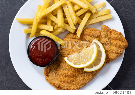 Wiener schnitzel with fried potatoes on black background Wiener schnitzel with fried potatoes on black background 99021402