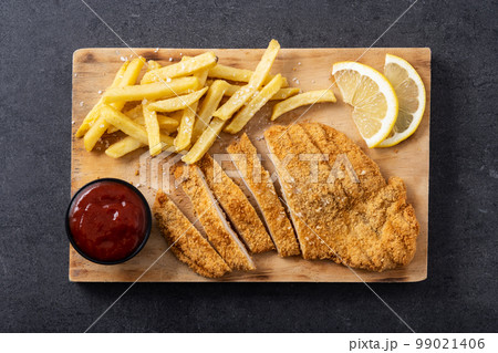 Wiener schnitzel with fried potatoes on black background 99021406