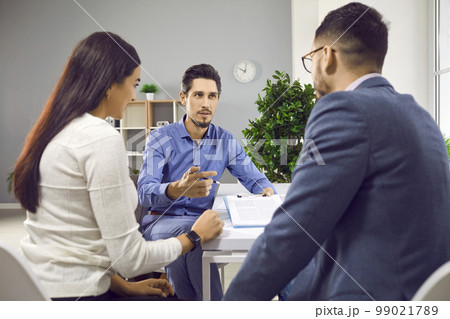 Professional real estate agent offering a young couple to sign a contract agreement 99021789