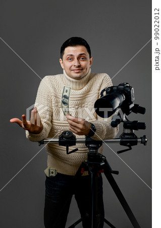 photographer with digital camera on tripod holding hundred dollar bills photographer with digital camera on tripod holding hundred dollar bills 99022012