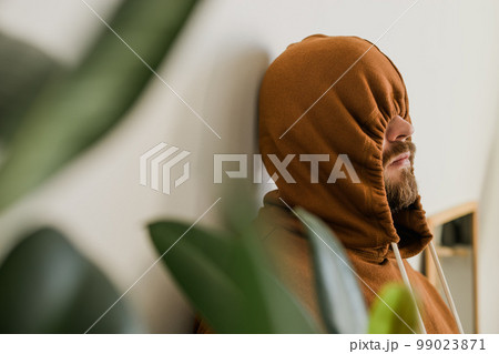 Depressed unhappy man covered hood her face - escapism and loneliness mental problem concept. Bipolar disorder and melancholy 99023871