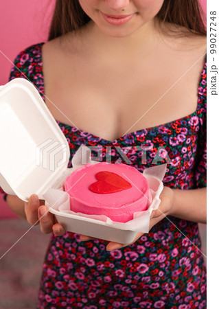Close-up of bento cake with heart on top in female hands 99027248