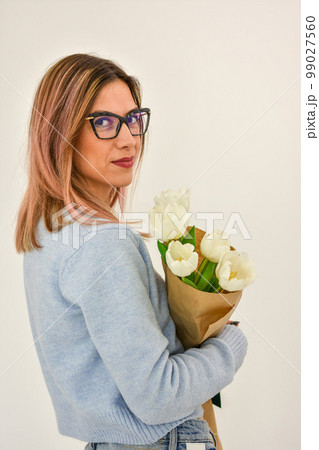 Bouquet of white tulips in a female hand on a white background. 99027560